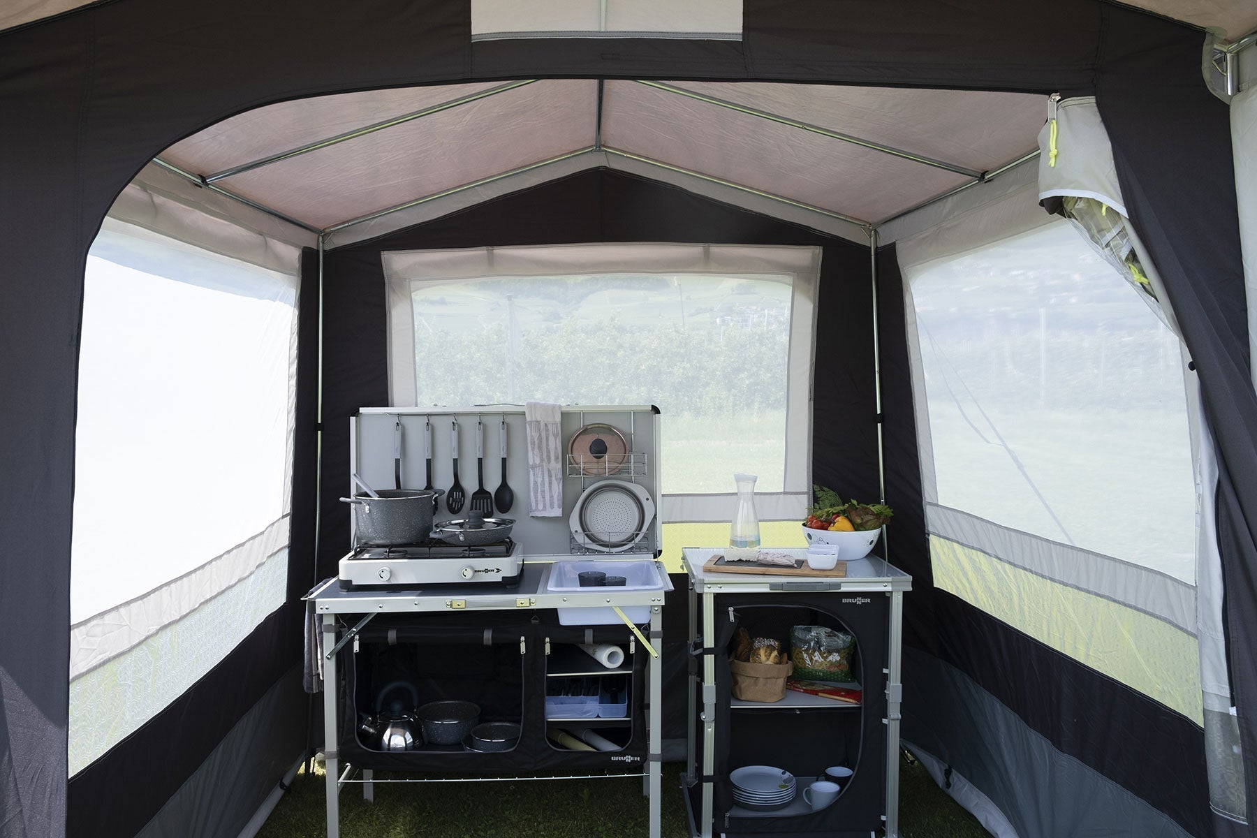 Интериор на палатка с кухненски принадлежности и маса, идеална за комфортно къмпингуване.