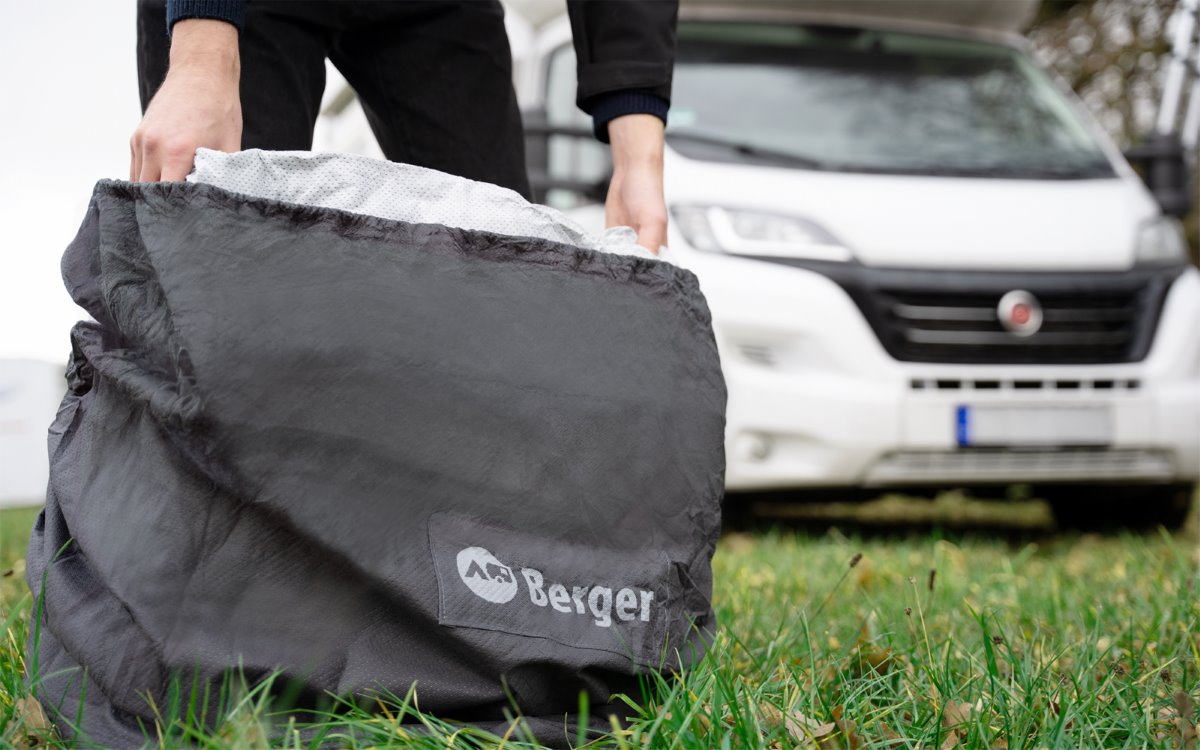 Покривало за каравана BERGER UV - цяло, водоустойчиво, дишащо, в ръцете на човек, на зелена трева.