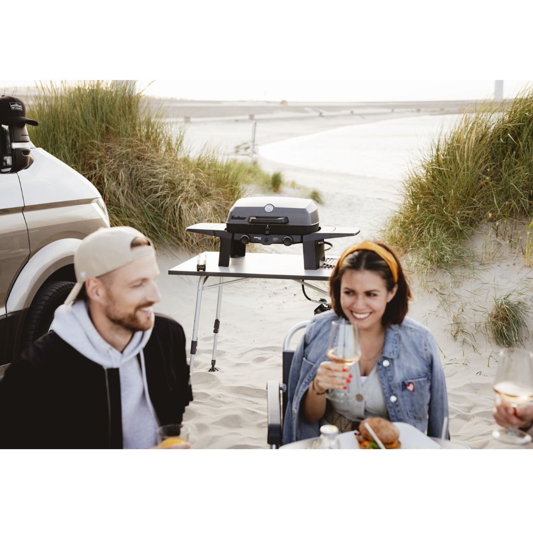 Хора, наслаждаващи се на къмпинг край морето с преносимо газово барбекю Enders Urban II Pro 30 mbar на отлична цена