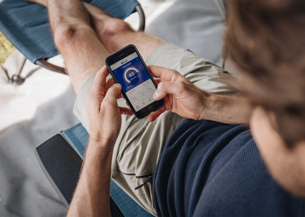 Мъж следи състоянието на Тягов акумулатор Berger LiFePO4 120Ah 12V с Bluetooth чрез мобилно приложение на телефона си.